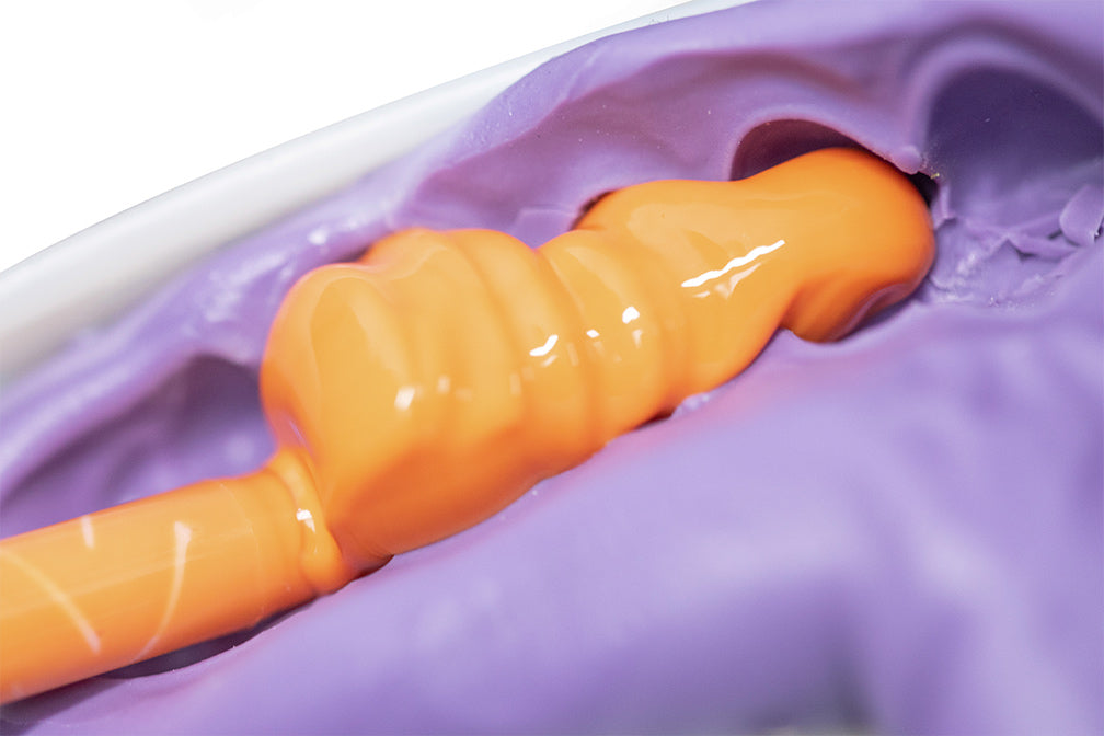 PERFIT Light Body dental impression material showing orange viscous material flowing into purple impression tray, demonstrating high-precision dental molding capabilities for crowns and bridges