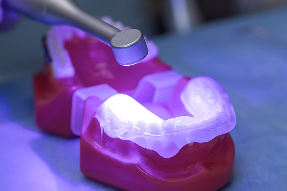 Transparent dental impression material PERFIT Regular Body being light-cured on pink dental mold, showcasing its extreme clarity and photopolymerization properties under UV light