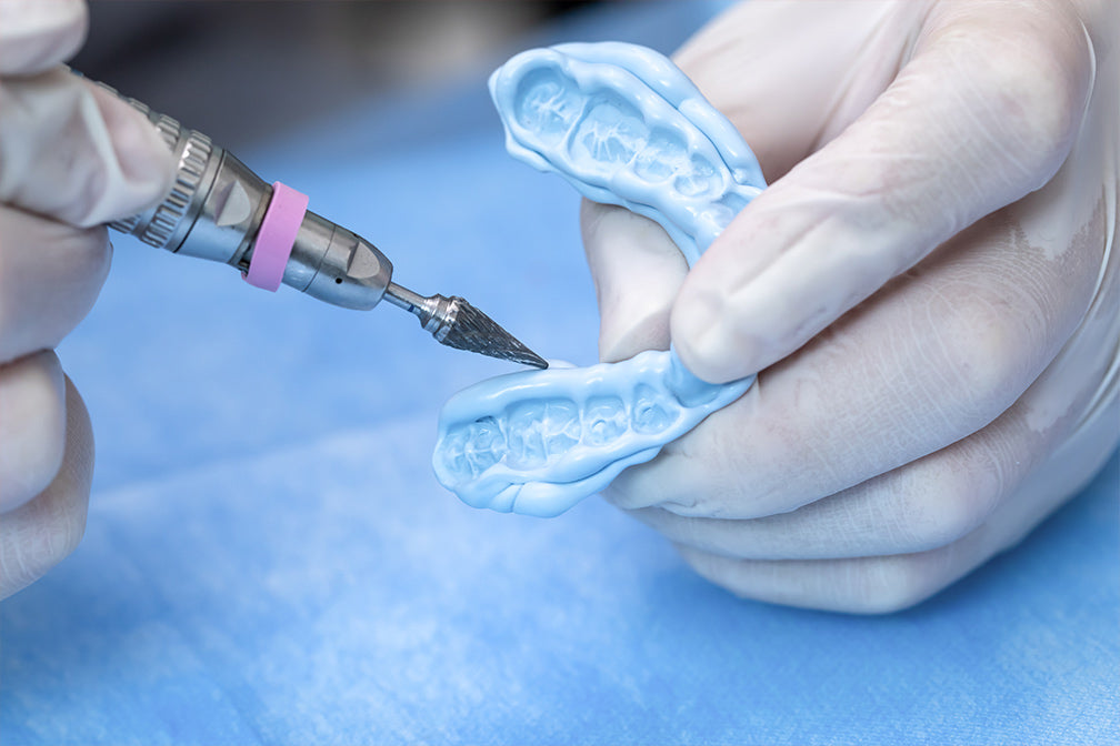 Dental professional applying PERFIT Bite Registration material into blue dental impression trays, demonstrating precise application technique for accurate occlusal registration during dental procedure