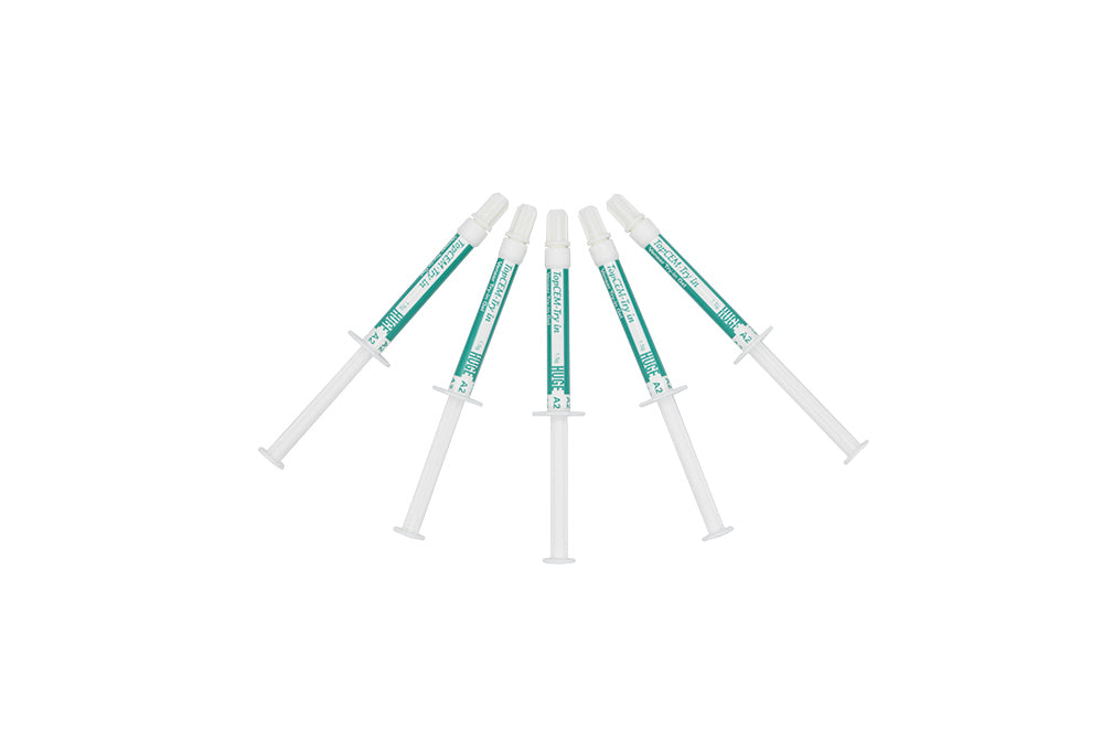 Five dental syringes with turquoise-colored try-in gel containing TopCEM Try-in Veneer Try-in Gel, arranged in a fan pattern against white background, featuring transparent dispensing tips for precise application