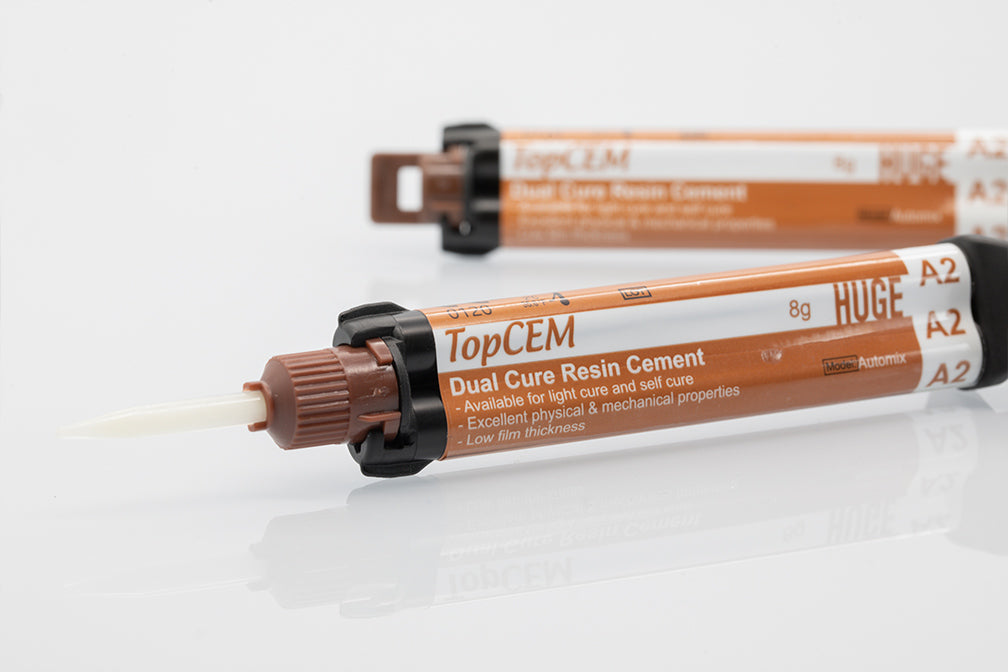 TopCEM Dual Cure Resin Cement syringes displayed on white background, showing brown-colored product packaging with clear labeling and dispensing tips, designed for professional dental restoration applications