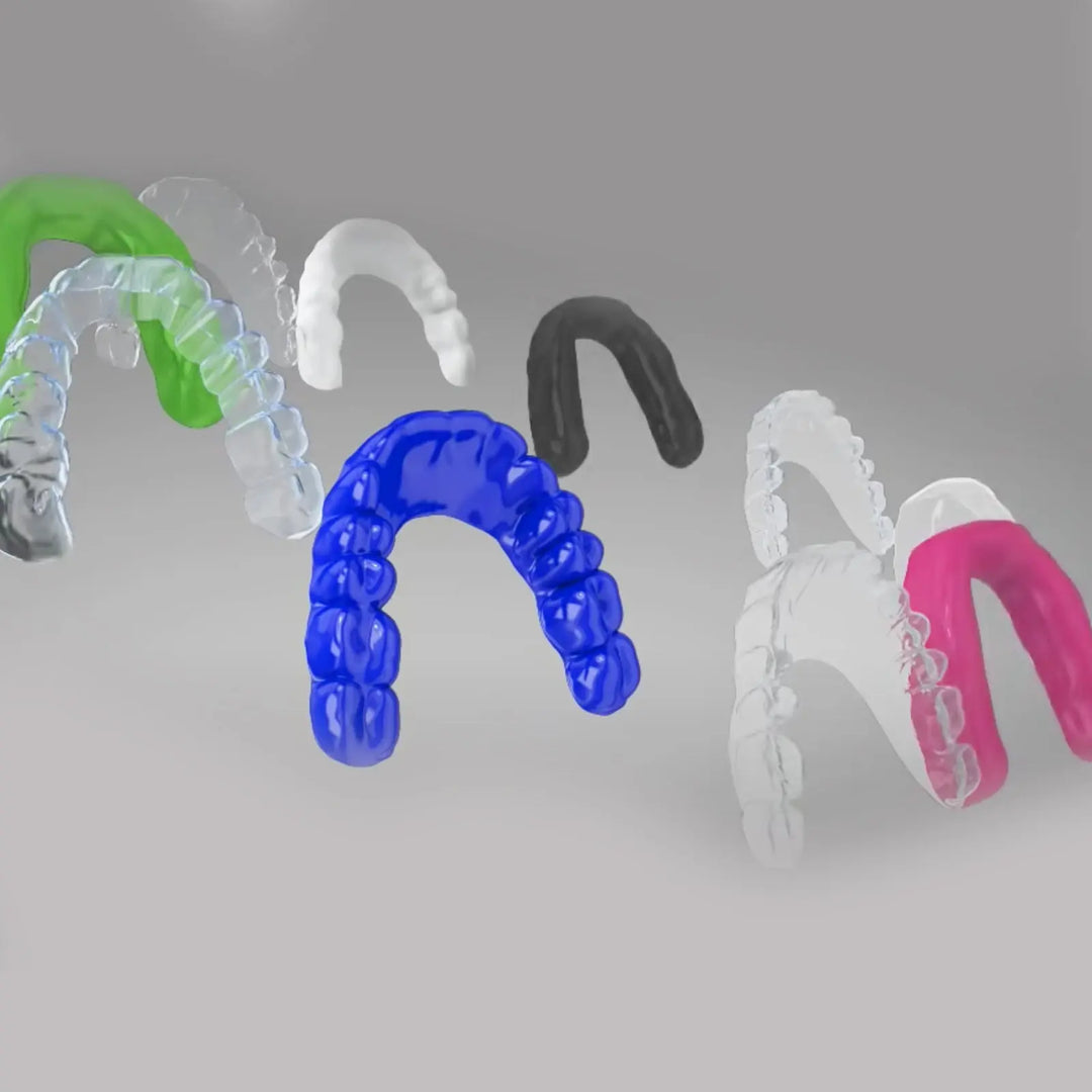 Colorful dental molds created by BIOART Dental Vacuum Forming Machine Laboratory Heat Molding Equipment PLASTVAC-P7, showcasing various transparent and opaque dental trays in green, blue, black, clear, and pink.