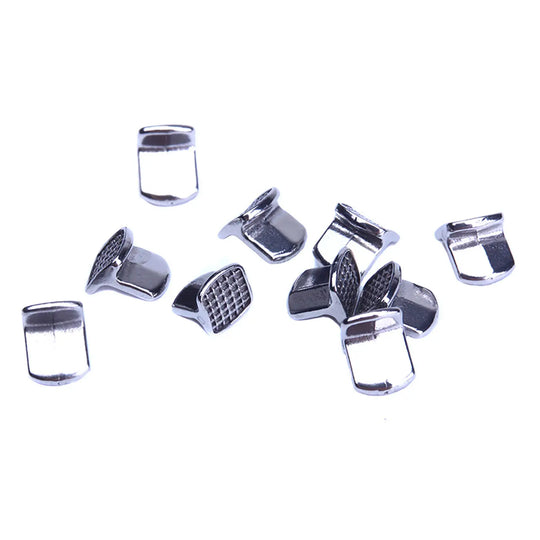 Bite Turbos Archwire Brace Buccal Tube Molar Band 10/Bag: Stainless steel orthodontic components scattered on white background. Small, shiny metal pieces with textured surfaces and curved edges, designed for dental braces and bite correction.