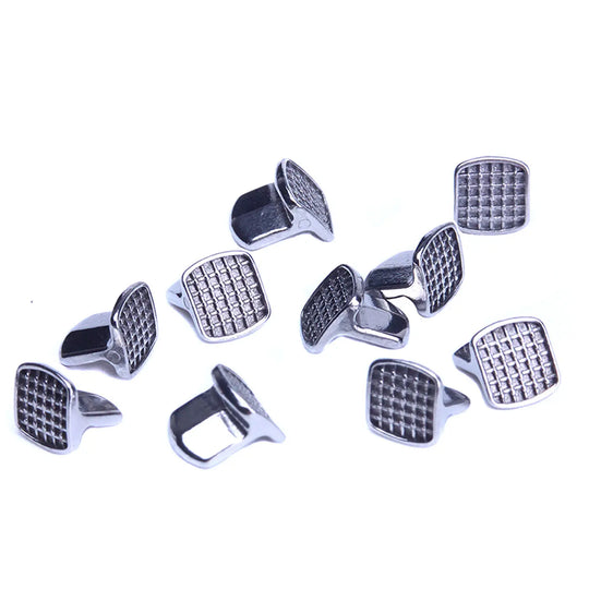 Bite Turbos Archwire Brace Buccal Tube Molar Band 10/Bag: Shiny metal orthodontic components with textured square surfaces, scattered on white background. Medical-grade stainless steel parts for comfortable patient wear and reliable bonding in dental procedures.