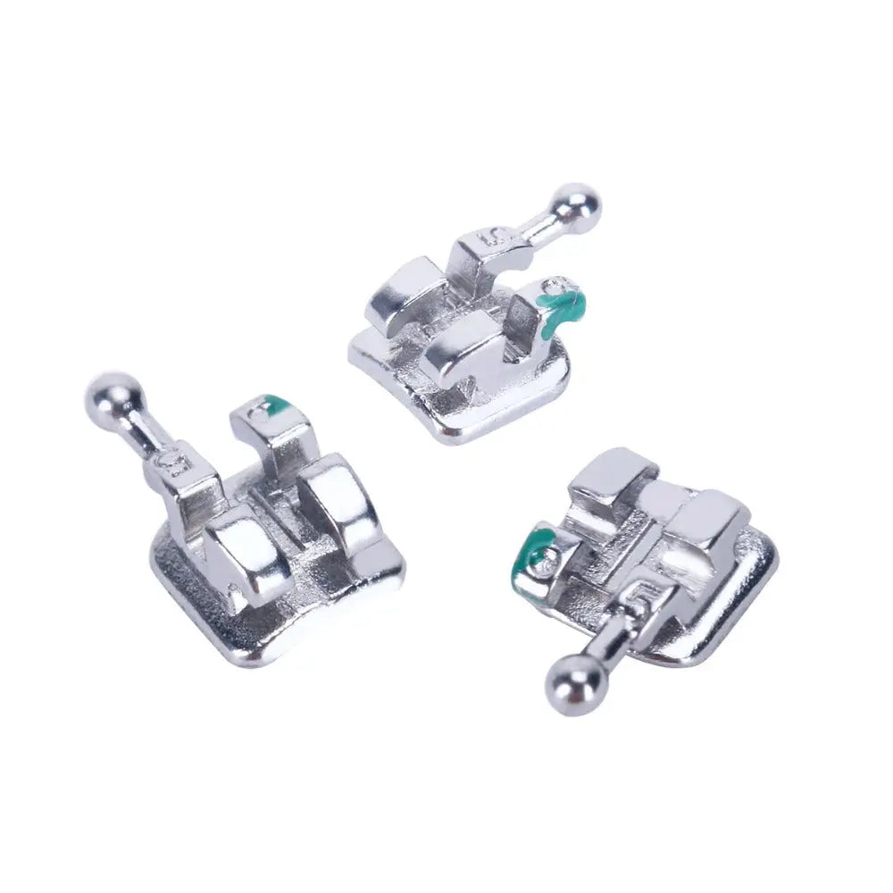 Dental Mini Metal Brackets Monoblock Roth .022/.018 Hooks on 345 20 Sets/Box: Close-up of three silver metal orthodontic brackets with green markings, showcasing the high-quality casting and precise design for dental applications