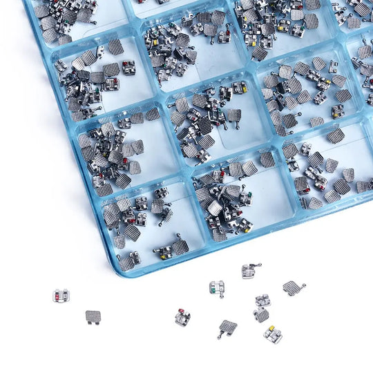 Dental Mini Metal Brackets Monoblock Roth .022/.018 Hooks on 345 20 Sets/Box displayed in blue compartmentalized tray. Multiple small metal orthodontic brackets sorted into individual sections, showcasing product quantity and organization for dental professionals.