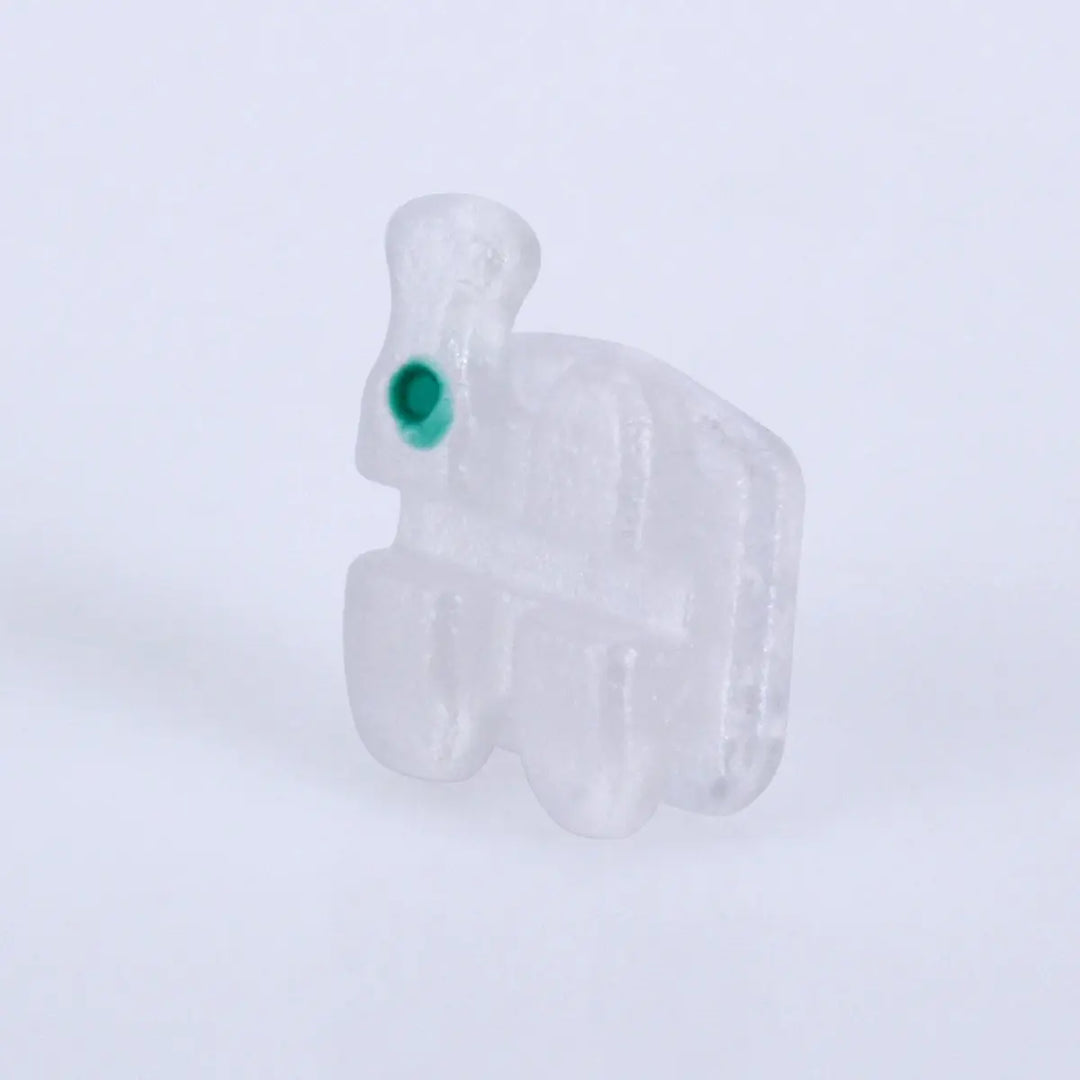 Ceramic Brackets Roth .018 Hooks 345 20pcs/Box: Close-up of a single transparent orthodontic bracket with a green dot, showcasing its low profile design and smooth edges for comfortable dental alignment and efficient tooth movement.