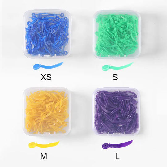 Dental Disposable Wedges With Hole Plastic Tooth Gap Wedge 4 Sizes 100pcs/Box: Four transparent boxes containing colorful dental wedges in blue, green, yellow, and purple, labeled XS, S, M, and L respectively. Each box showcases wedges with curved shapes and small holes at one end.