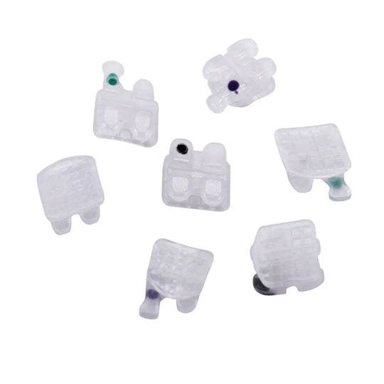 Dental Orthodontic Ceramic Brackets Mesh Base Full Size 20pcs/Box: Various white ceramic brackets with color-coded dots displayed on a plain background, showcasing different shapes and sizes for orthodontic use.