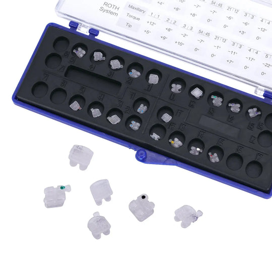 Dental Orthodontic Ceramic Brackets Mesh Base Full Size 20pcs/Box displayed in open blue case with ROTH system chart. Small white ceramic brackets visible, showcasing color-coded design for easy identification and mesh base for strong adhesion.