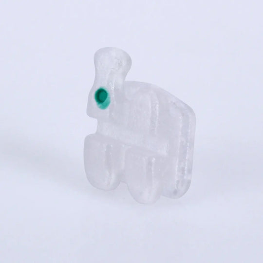 Dental Orthodontic Ceramic Brackets Full Size Hooks 345 20pcs/Box: Close-up of a single clear ceramic orthodontic bracket with a green dot, showcasing its low-profile design and mesh base for optimal tooth adhesion and alignment.