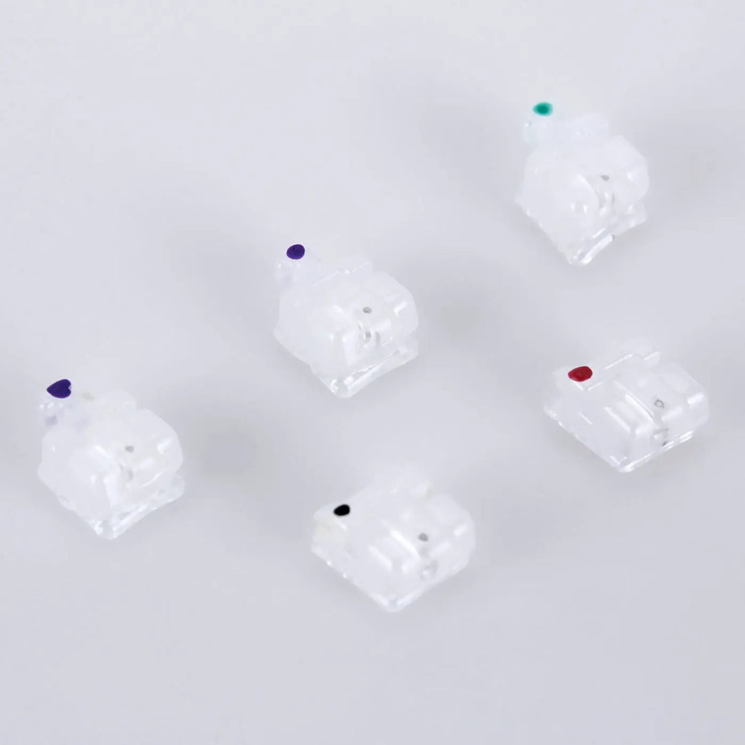 Dental Self-ligating Ceramic Bracket Roth 0.022 Hooks on 345 20pcs/Box: Set of five translucent orthodontic brackets with color-coded dots, arranged in a pentagon formation on a light background. Showcases low-profile design and smooth edges for patient comfort.