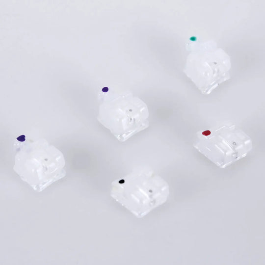 Dental Self-ligating Ceramic Bracket Roth 0.022 Hooks on 345 20pcs/Box: Set of five translucent orthodontic brackets with color-coded dots, arranged in a pentagon formation on a light background. Showcases low-profile design and smooth edges for patient comfort.