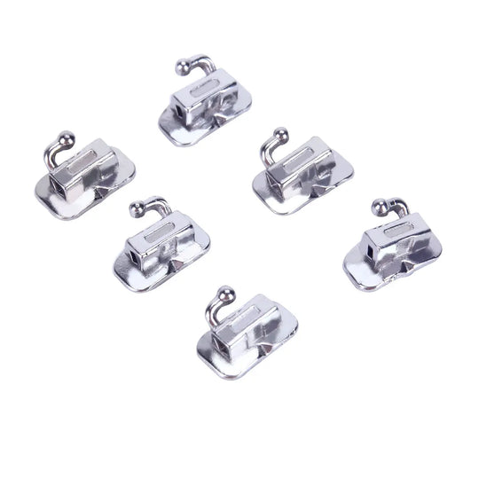 Buccal Tube 1st Molar Bondable Monoblock Non-convertible Roth 0.018 50Sets/Bx: Six silver metallic orthodontic buccal tubes arranged in two rows, showcasing their compact design and curved hooks for dental application