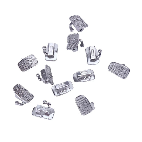 Buccal Tube 1st Molar Bondable Monoblock Non-convertible Roth 0.022 20Sets/Bx displayed as multiple silver-colored metal orthodontic components arranged on a white background, showcasing the detailed design and various parts of the dental buccal tubes used in orthodontic treatments.