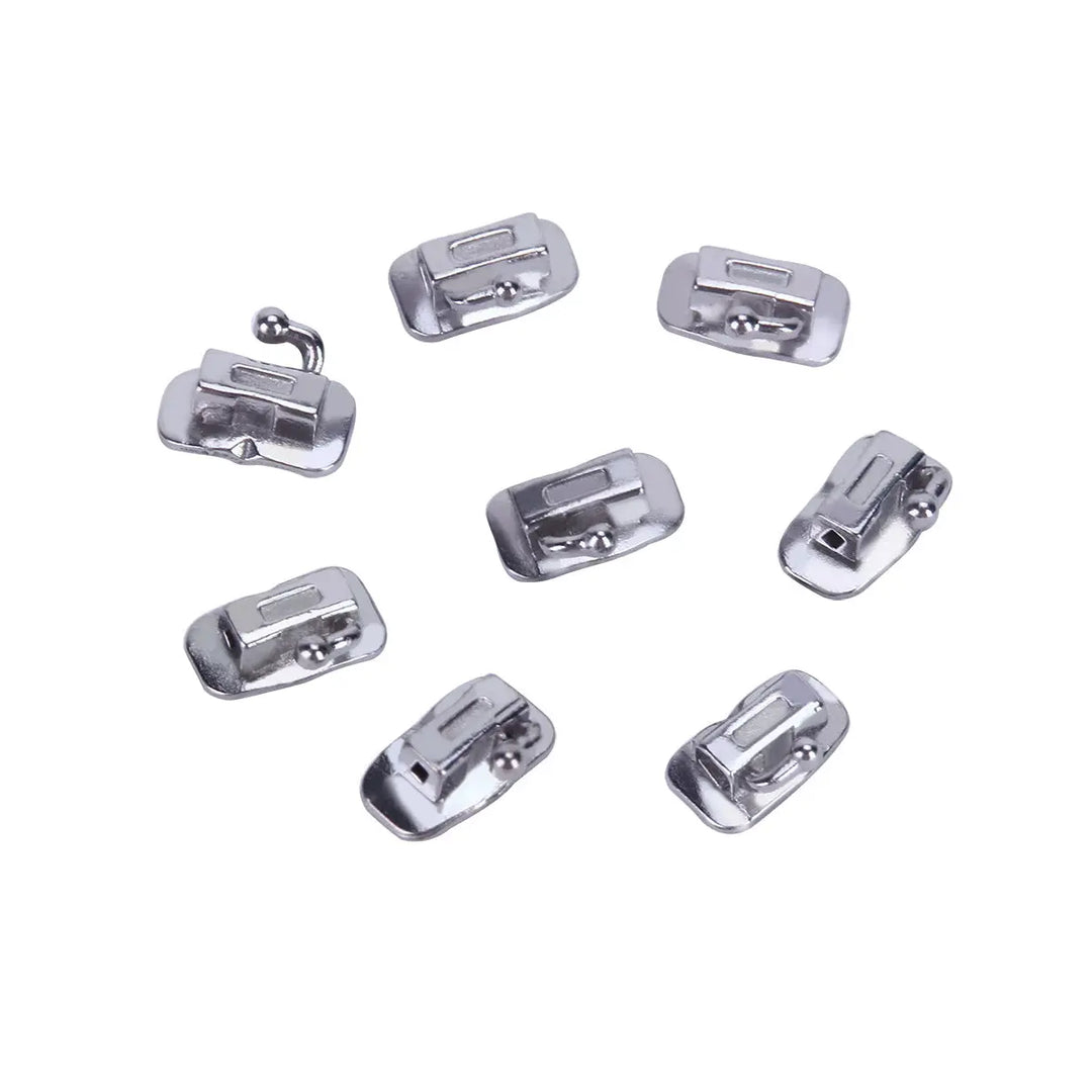 Buccal Tube 1st Molar Bondable Monoblock Non-convertible Roth 0.022 20Sets/Bx: Multiple silver-colored metal orthodontic buccal tubes arranged on white background. Each tube has a rectangular opening and a curved base for bonding to teeth.