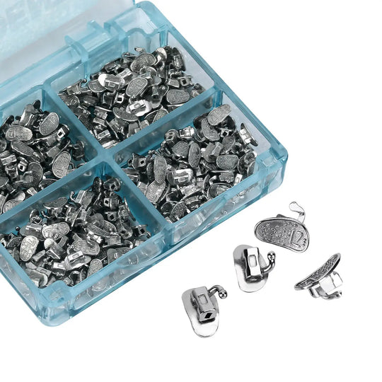 Buccal Tube 2nd Molar Bondable Monoblock Non-convertible Roth 0.022 50Sets/Bx displayed in a blue plastic organizer box. Multiple small metal orthodontic components sorted into compartments, with a few pieces shown separately outside the box for detail.