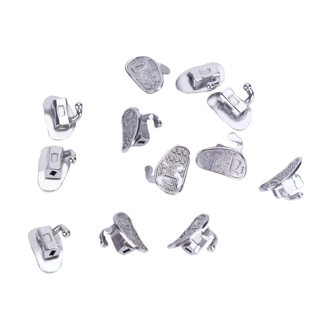 Buccal Tube 2nd Molar Bondable Monoblock Non-convertible Roth 0.022 50Sets/Bx: Multiple silver-colored dental orthodontic buccal tubes scattered on white background, showcasing various angles and designs of the product for second molar applications.