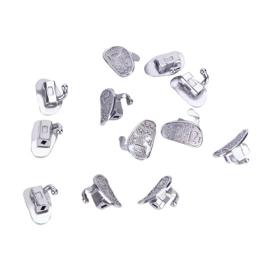 Buccal Tube 2nd Molar Bondable Monoblock Non-convertible Roth 0.022 20Sets/Bx - Multiple silver-colored dental orthodontic buccal tubes scattered on white background, showing various angles of the single tube design for 2nd molars, highlighting their bondable and non-convertible features for orthodontic treatment.