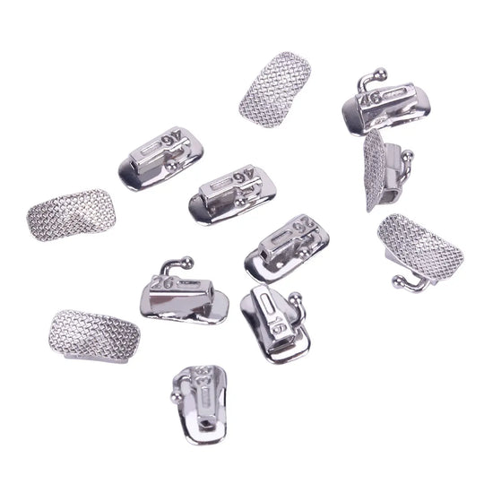 Assorted Buccal Tube 1st Molar Bondable Split Non-Convertible Roth 0.018 dental orthodontic components displayed, including metal tubes and mesh pads for bonding. Various sizes and orientations shown for upper and lower molars, representing the 50-set box product.