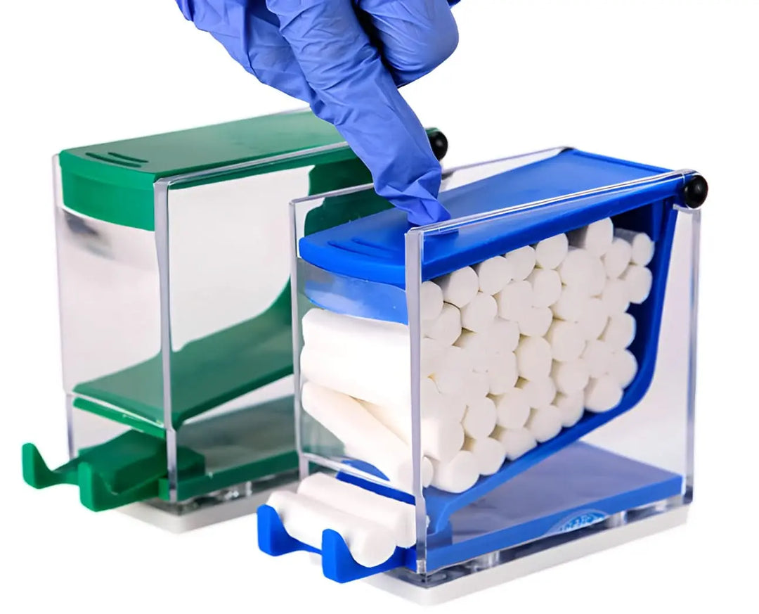 Cotton Roll Dispenser (ADS210) (ADS211) featuring transparent blue and green storage boxes filled with white cotton rolls. A gloved hand is shown opening the blue dispenser, demonstrating the push-down mechanism for easy access to dental supplies.