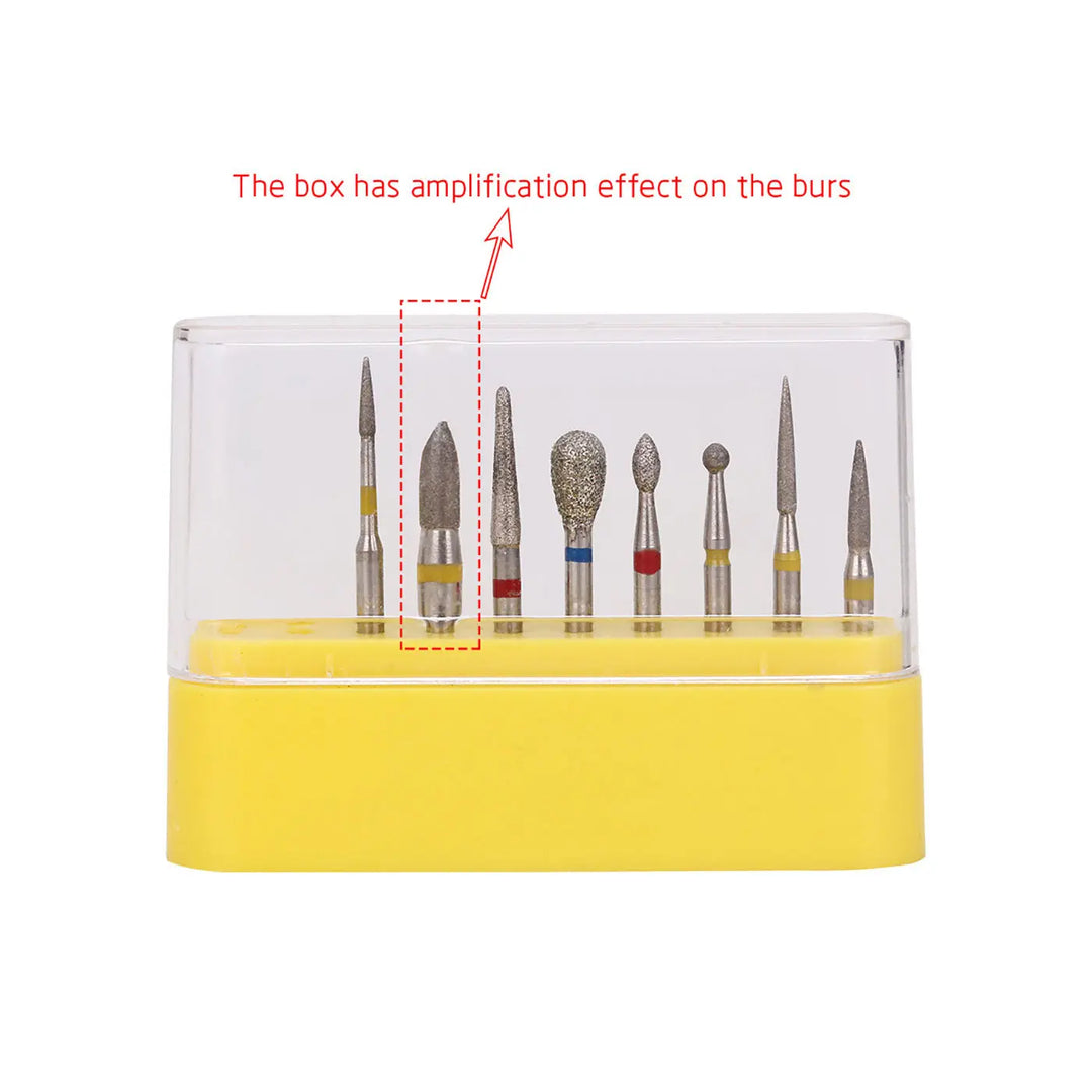 Dental Diamond Bur FG-114 Composite Resin Kit 8pcs/Kit displayed in a clear plastic case with yellow base. Various bur shapes and sizes visible, including round, pointed, and cylindrical types. Text indicates magnification effect on burs.