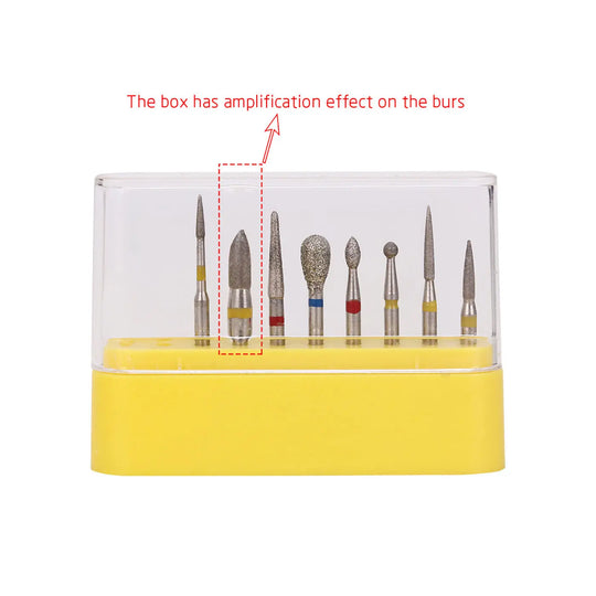 Dental Diamond Bur FG-114 Composite Resin Kit 8pcs/Kit displayed in a clear plastic case with yellow base. Various bur shapes and sizes visible, including round, pointed, and cylindrical types. Text indicates magnification effect on burs.