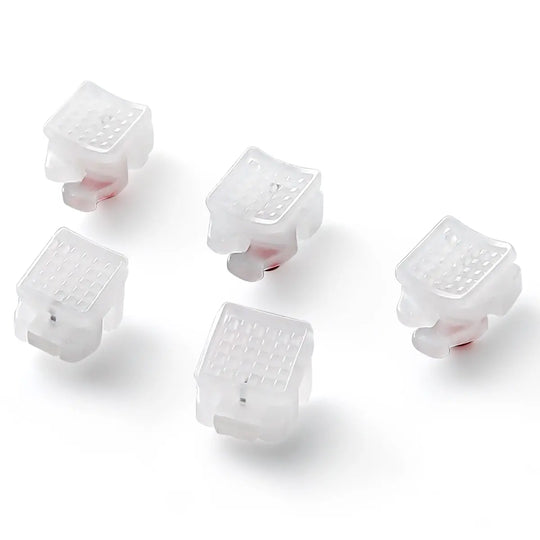 Dental Self-ligating Ceramic Brackets Clear Roth/MBT 0.022 with hook 3,4,5 - Close-up view of five translucent white orthodontic brackets with pink inner components, showcasing their smooth, square design and self-ligating mechanism for efficient tooth alignment.