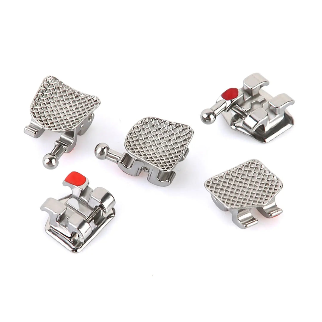 Dental Mini Metal Brackets MBT Slot .018 Hooks on 3 20pcs/Pk: Close-up of silver orthodontic brackets with textured mesh pads and small red markers, showcasing their low-profile design and hook features for precise teeth alignment